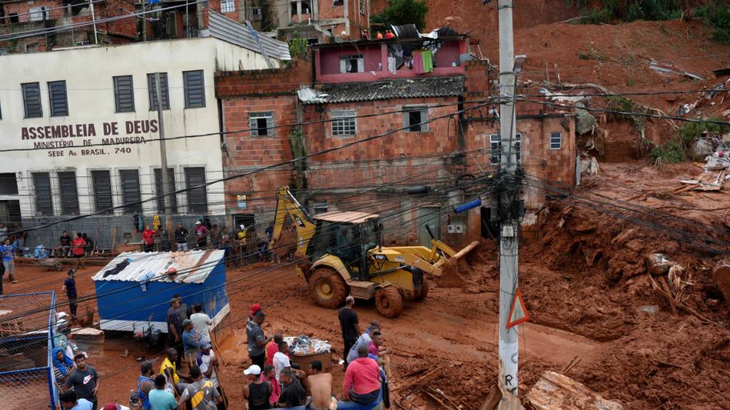 Feuerwehrleute und Mitarbeiter des Zivilschutzes helfen im brasilianischen Bundesstaat Minas Gerais an der Stelle, an der Häuser aufgrund von heftigen Regenfällen und Überschwemmungen in Juiz de Fora eingestürzt sind. Foto: Silvia Izquierdo/AP/dpa
