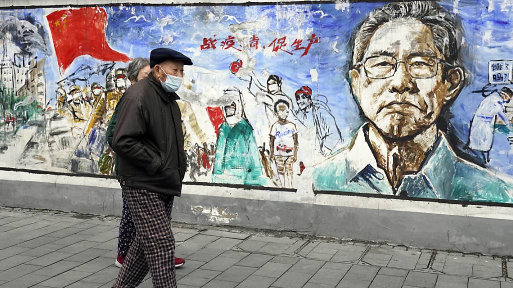 Anwohner gehen in der zentralchinesischen Stadt Wuhan, in der das Coronavirus zum ersten Mal nachgewiesen wurde, an einem Wandgemälde mit dem Titel «Erinnerungen» vorbei. Foto: Ng Han Guan/AP/dpa