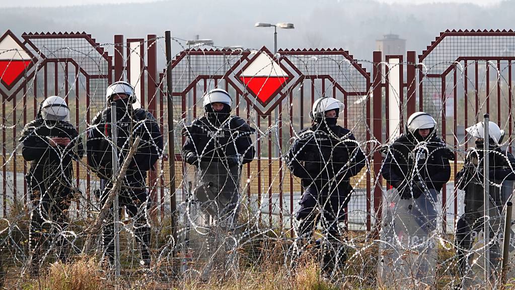 Polnische Sicherheitskräfte stehen an der Grenze hinter Stacheldraht. Foto: Ulf Mauder/dpa