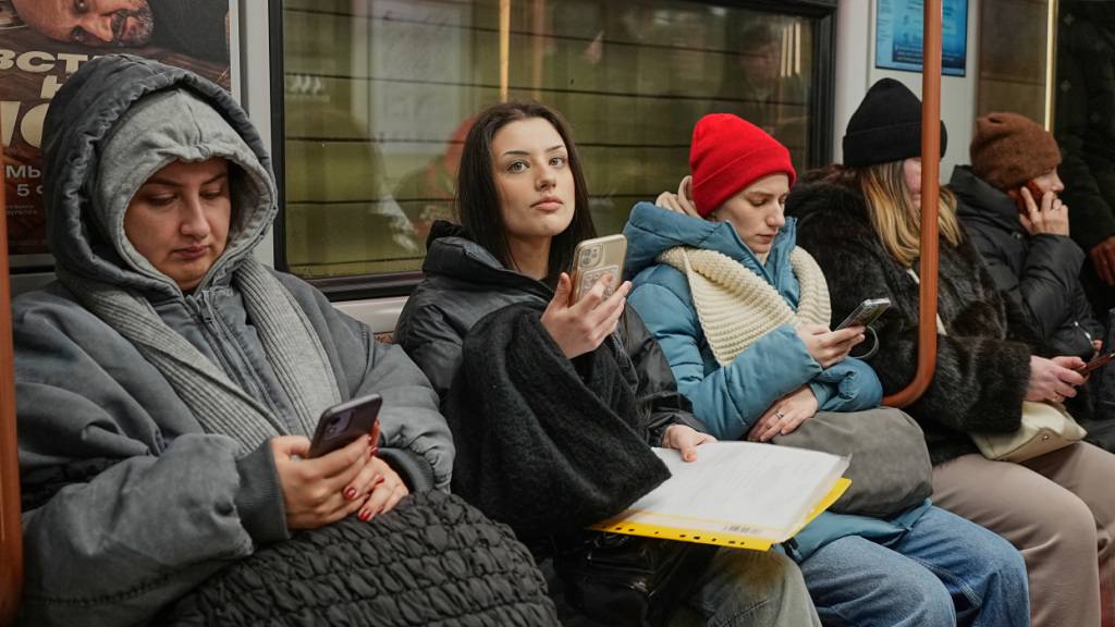 ARCHIV - Fahrgäste schauen auf ihre Smartphones, während sie in der Moskauer U-Bahn fahren. Foto: Alexander Zemlianichenko/AP/dpa/Archivbild