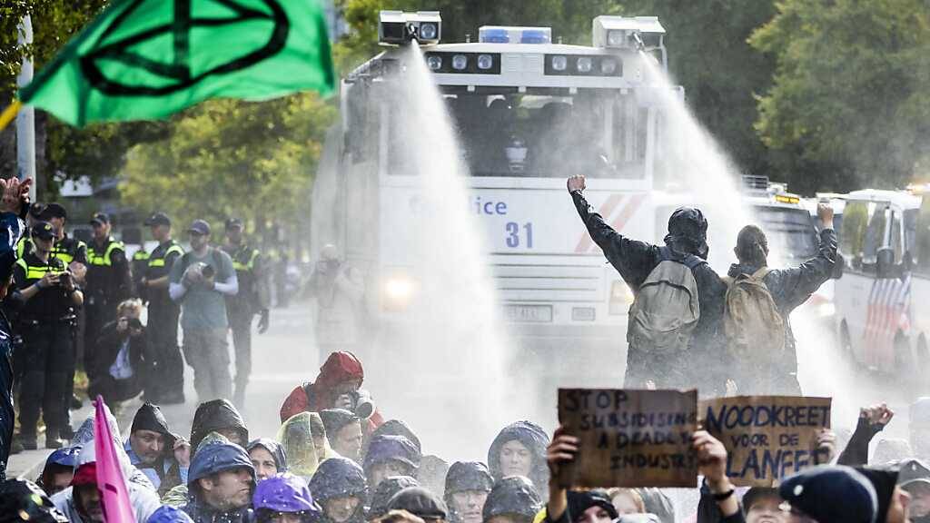Die Polizei setzt Wasserwerfer gegen Klimaaktivisten ein, die erneut auf der Fahrbahn der A12 nahe Den Haag protestieren. Foto: Remko De Waal/ANP/dpa