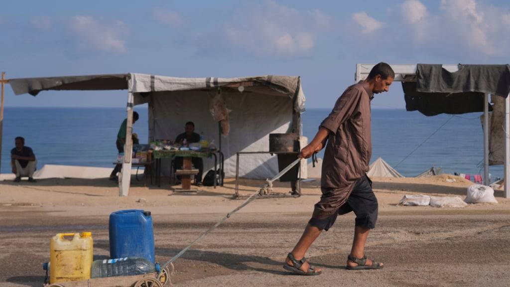 dpatopbilder - Ein Mann zieht einen Wagen mit Kanistern und Plastikflaschen mit Wasser, nachdem er es in einem Lager für Vertriebene gesammelt hat. Foto: Abdel Kareem Hana/AP/dpa