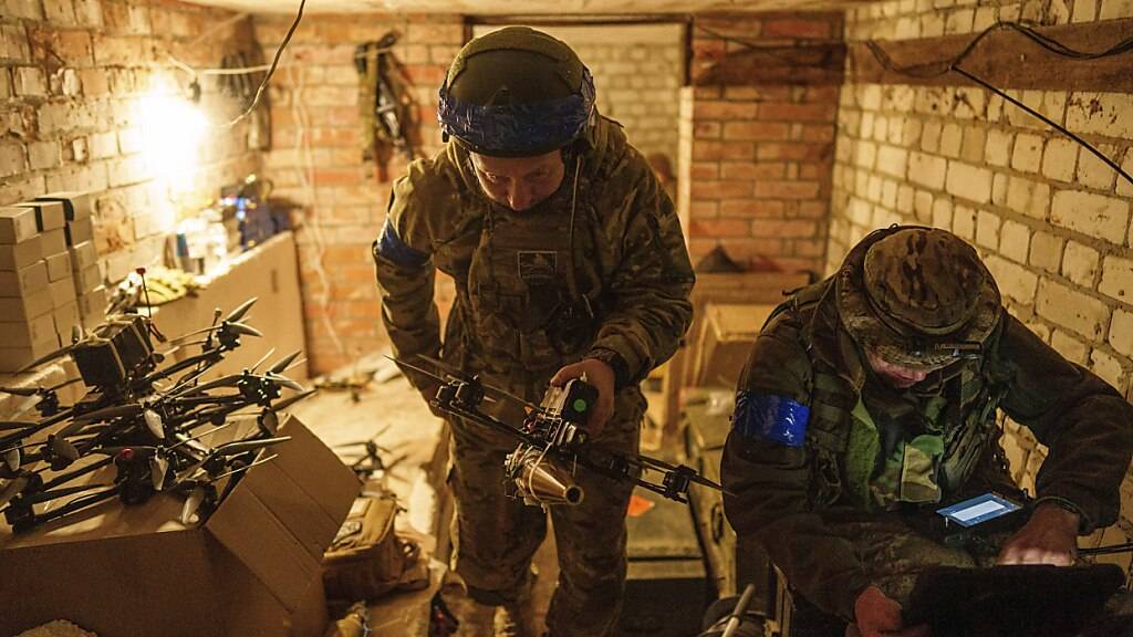 Ein ukrainischer Soldat trägt eine Selbstmord-FPV-Drohne in die Startposition, bevor er sie über russische Stellungen in der Region Charkiw fliegen lässt. Foto: Evgeniy Maloletka/AP/dpa