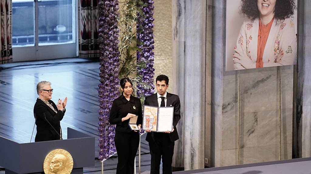Ali (r) und Kiana Rahmani (M) halten die Medaille und die Urkunde während der Verleihung des Friedensnobelpreises 2023 im Rathaus von Oslo entgegen. Ali und Kiana nehmen den Friedensnobelpreis stellvertretend für ihre Mutter entgegen, die im Iran inhaftiert ist. Mohammadi erhält den Friedensnobelpreis 2023 für ihren Kampf gegen die Unterdrückung der Frauen im Iran und den Kampf für Menschenrechte und Freiheit für alle. Foto: Fredrik Varfjell/NTB/dpa