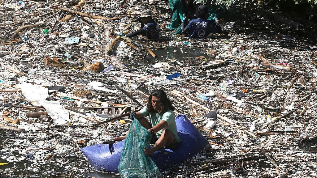Ein Freiwilliger sammelt in Pecatu auf Bali Müll aus einem Fluss. Während der Monsunzeit sind einige Flüsse mit Plastikmüll und Unrat übersät. Foto: Firdia Lisnawati/AP