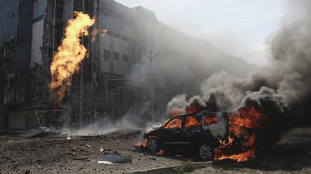 dpatopbilder - ARCHIV - Ein brenndes Auto in Charkiw vor einem Geschäftszentrum, das durch russische Angriffe beschädigt wurde. Foto: George Ivanchenko/AP/dpa