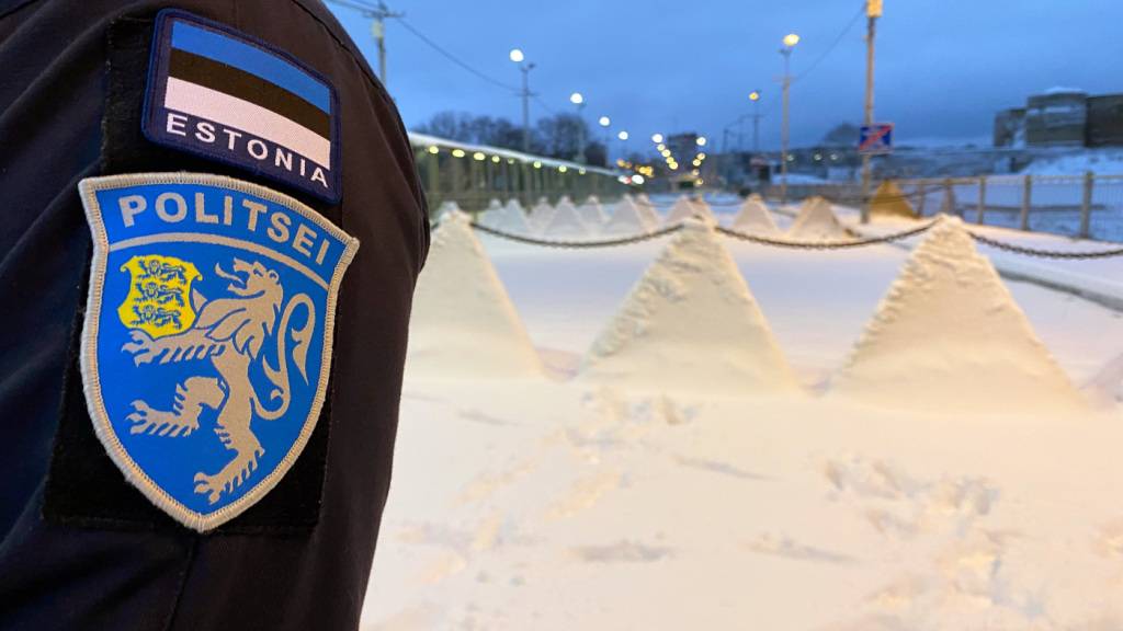 ARCHIV - Ein Wappen der estnischen Polizei und die estnische Flagge sind auf der Uniform eines estnischen Polizisten angebracht, der auf der Grenzbrücke von der estnischen Stadt Narva nach Russland steht. Foto: Alexander Welscher/dpa