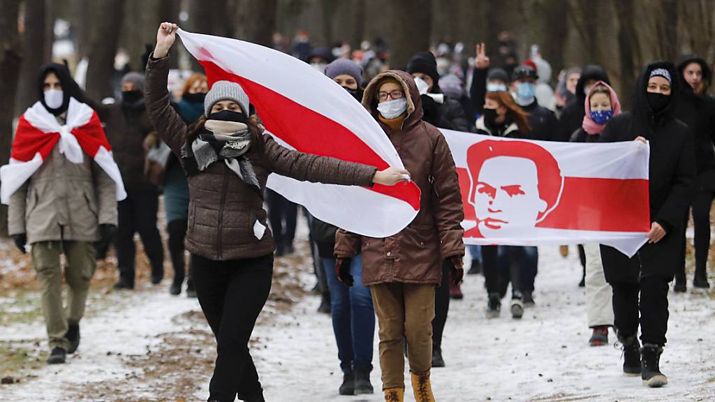 dpatopbilder - Demonstranten mit Mund-Nasen-Schutz tragen bei einer Kundgebung, auf der sie den Rücktritt von Machthaber Lukaschenko fordern, Fahnen in den Farben der früheren belarussischen Nationalflagge. Foto: ---/AP/dpa