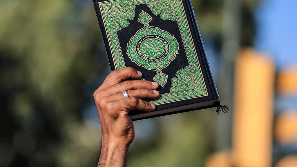 Ein Mann hält ein Exemplar des Koran während eines Protests. Foto: Ameer Al-Mohammedawi/dpa