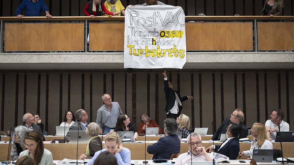 Impfgegner sorgten für eine Störaktion im Zürcher Parlament. Ein Mitarbeiter der Parlamentsdienste reisst ein beschriftetes Leintuch von der Tribüne.