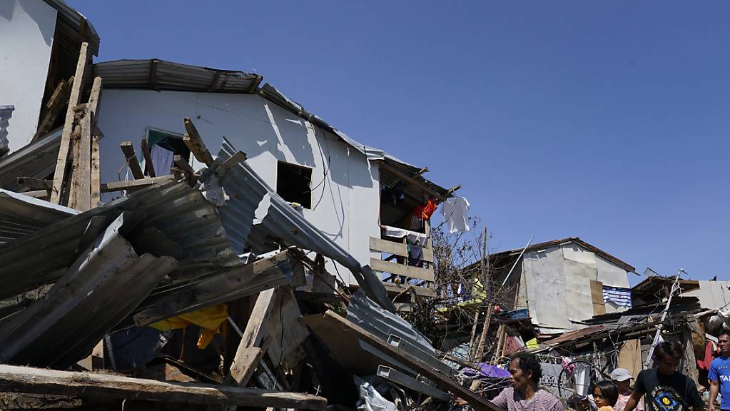 Bewohner suchen nach Habseligkeiten in den Trümmern von zerstörten Häusern. Der Tropensturm «Rai» traf am Donnerstagnachmittag (Ortszeit) mit heftigen Winden und starken Regenfällen auf die Philippinen. Nach Angaben des nationalen Katastrophenschutzes starben dadurch mindestens 31 Menschen. Foto: Jay Labra/AP/dpa