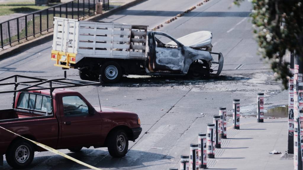 Ein Fahrzeug steht ausgebrannt auf einer Straße in Guadalajara. Nach dem Tod von Mexikos mächtigstem Drogenboss wurden in mehreren Bundesstaaten Straßen mit brennenden Autos, Lastwagen und Bussen gesperrt. Foto: Alejandra Leyva/AP/dpa