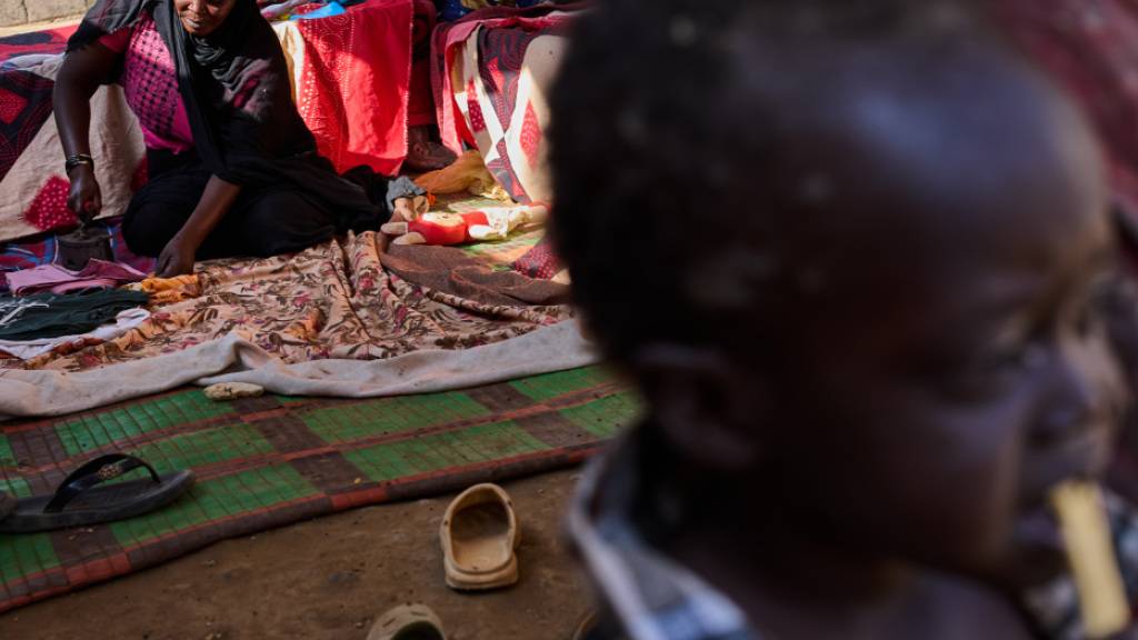 Die sudanesische Binnenvertriebene Safia Abbakar bügelt in ihrem provisorischen Zelt im Lager Al Heshan am Rande von Port Sudan. Foto: Bernat Armangue/AP/dpa