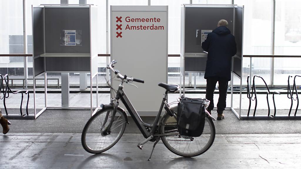 Ein Fahrrad steht vor Wahlkabinen, die neben Fahrradständern aufgebaut sind. Die Wahlen zum neuen niederländischen Parlament haben begonnen. Rund 13 Millionen Bürger sind aufgerufen, die 150 Abgeordneten der Zweiten Kammer zu wählen. Wegen der Corona-Pandemie wird die Parlamentswahl zum ersten Mal an insgesamt drei Tagen stattfinden.