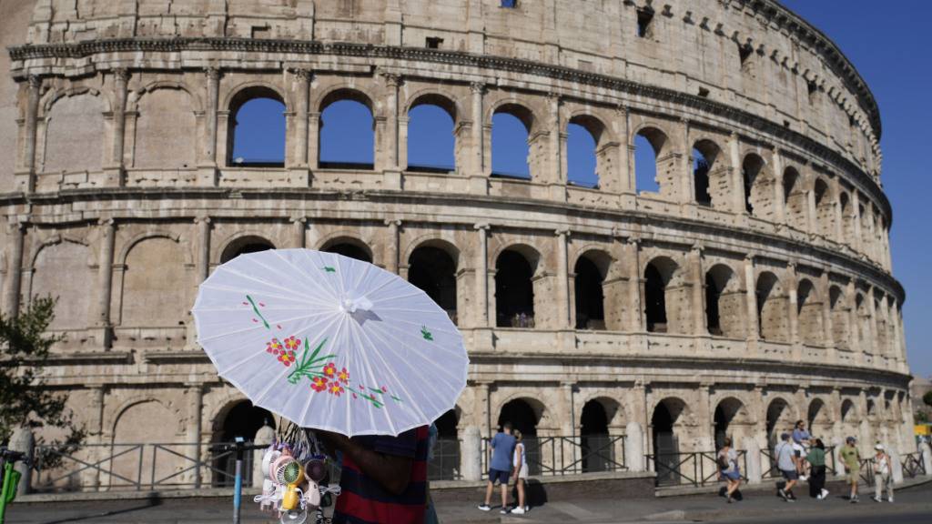 ARCHIV - Ein Mann verkauft Regenschirme vor dem Kolosseum. Foto: Gregorio Borgia/AP/dpa/Archivbild