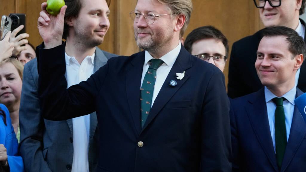 Der Vorsitzende der Partei Jabloko, Nikolai Rybakow (Mitte), hält nach einer Anhörung vor dem Obersten Gerichtshof Russlands in Moskau einen Apfel hoch - das Symbol seiner Partei. Foto: Pavel Bednyakov/AP/dpa/Archivbild