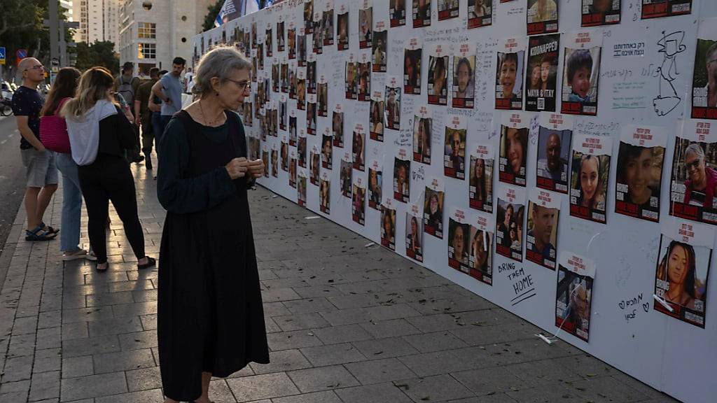 Israelis betrachten Fotos von Menschen, die im Gazastreifen vermisst und gefangen gehalten werden. Foto: Petros Giannakouris/AP/dpa