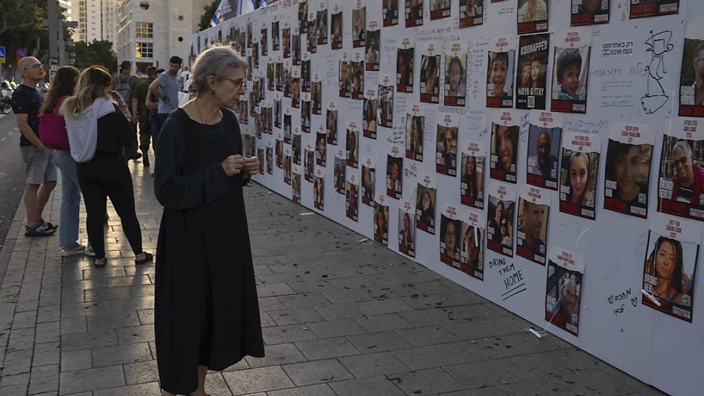 Israelis betrachten Fotos von Menschen, die im Gazastreifen vermisst und gefangen gehalten werden. Foto: Petros Giannakouris/AP/dpa
