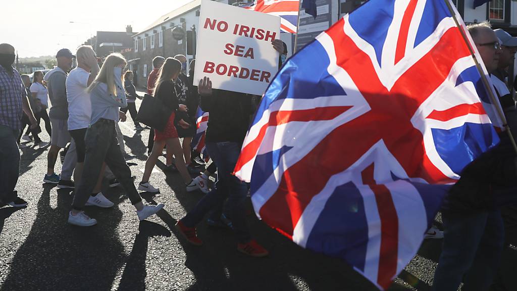 ARCHIV - Demonstranten halten britische Fahnen und ein Schild mit der Aufschrift «No Irish Sea Border» bei einem Protest protestantischer Loyalisten gegen das sogenannte Nordirland-Protokoll. Foto: Brian Lawless/PA Wire/dpa