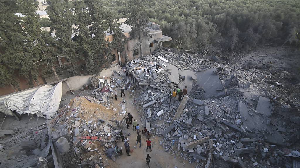 Palästinenser stehen vor einem Gebäude in Rafah im Gazastreifen, das bei einem israelischen Luftangriff zerstört wurde. Foto: Hatem Ali/AP/dpa