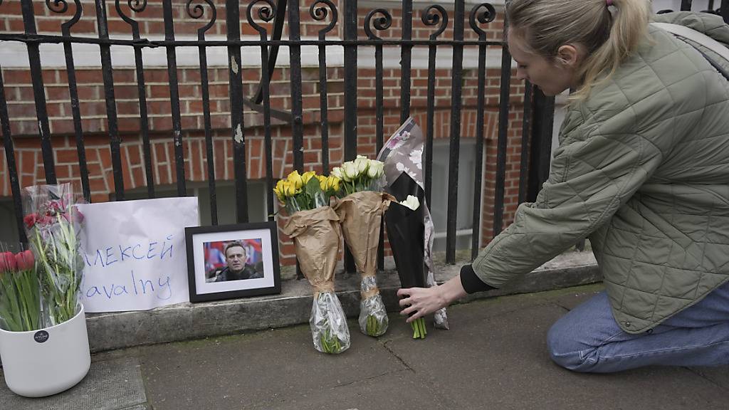 Eine Frau legt gegenüber der russischen Botschaft in London Blumen nieder. Foto: Kin Cheung/AP/dpa