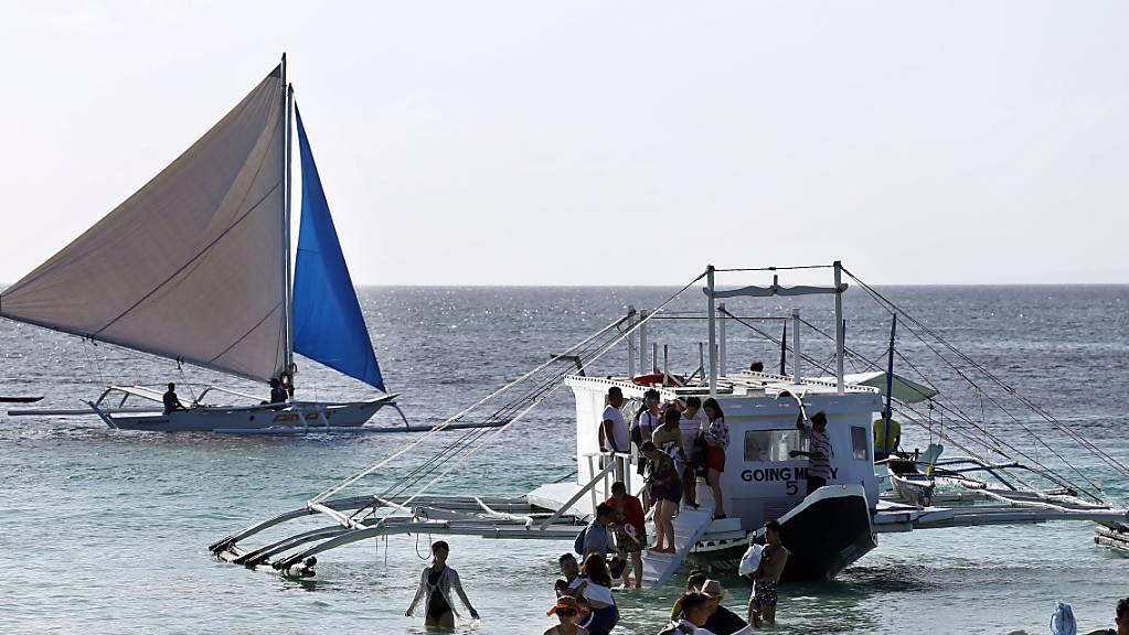 ARCHIV - Eine Gruppe von Touristen steigt am Strand von Boracay aus einem Boot. Die Philippinen öffnen ab kommendem Monat erstmals seit zwei Jahren wieder ihre Grenzen für internationale Touristen. Das kündigte Regierungssprecher Karlo Nograles am Freitag an. Foto: Alejandro Ernesto/dpa