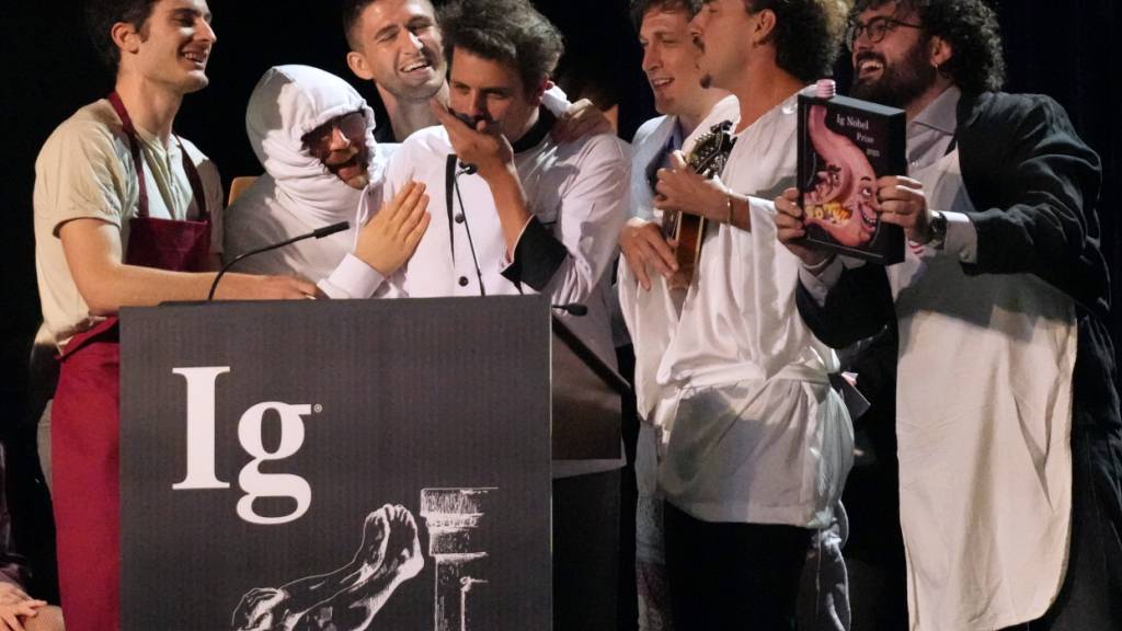 ARCHIV - Der Ig-Nobelpreis für Ernährung wird von Daniele Dendi, Gabriel H. Segniagbeto, Roger Meek und Luca Luiselli entgegengenommen, die untersucht haben, inwieweit eine bestimmte Eidechsenart bestimmte Sorten von Pizza isst. Foto: Robert F. Bukaty/AP/dpa