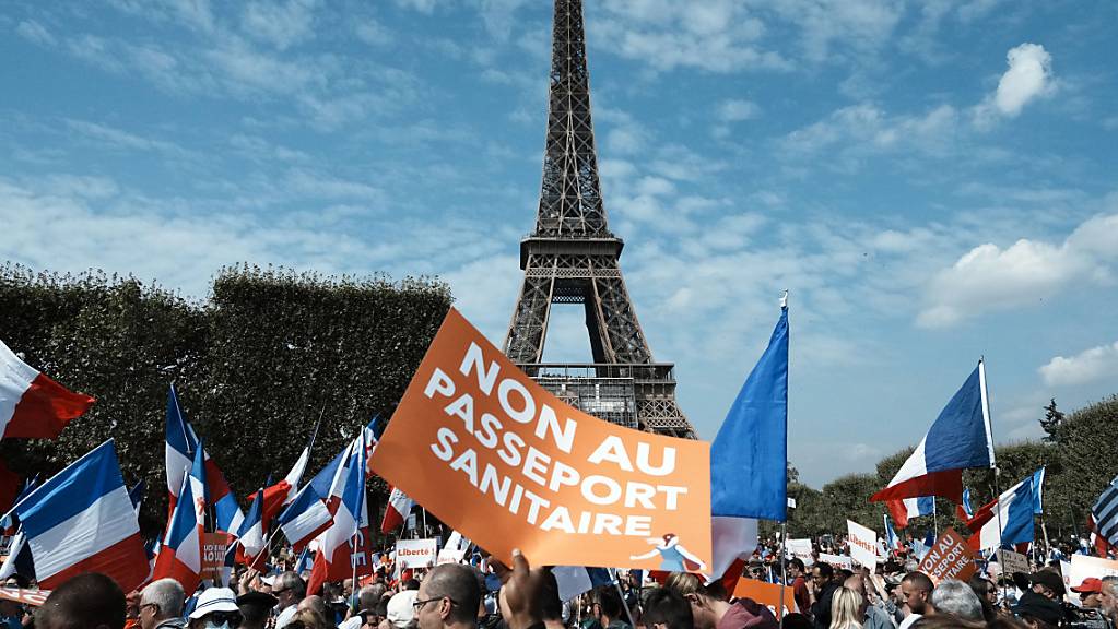 Ein Demonstrant hält während einer Demonstration gegen den Gesundheitspass vor dem Eiffelturm ein Plakat mit der Aufschrift «Nein zum Gesundheitspass» («Non Au Passeport Sanitaire»). Foto: Thibault Camus/AP/dpa