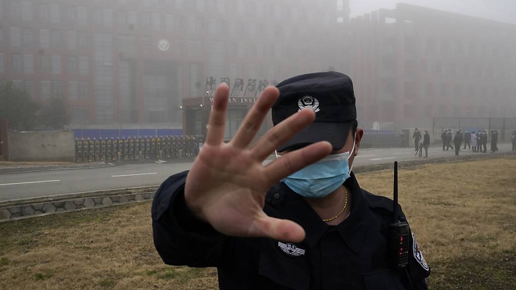 ARCHIV - Eine Sicherheitsperson vom Wuhan Instituts für Virologie (WIV) hindert Journalisten an ihrer Arbeit nachdem ein Team der Weltgesundheitsorganisation (WHO) eintraf (Archivbild). Foto: Ng Han Guan/AP/dpa