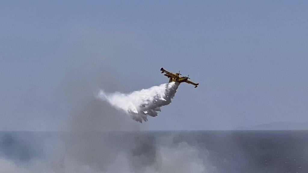 dpatopbilder - Ein Löschflugzeug wirft Wasser in der Küstengegend von Palaia Fokaia, südlich von Athen, ab. Foto: Giorgos Delveroudis/AP/dpa
