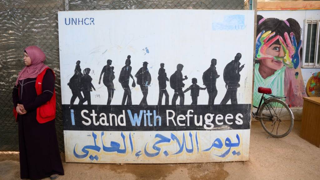 ARCHIV - Eine Frau steht im jordanischen Flüchtlingslager Saatari vor einem Plakat mit der Aufschrift «I stand with Refugees». Foto: Bernd von Jutrczenka/dpa