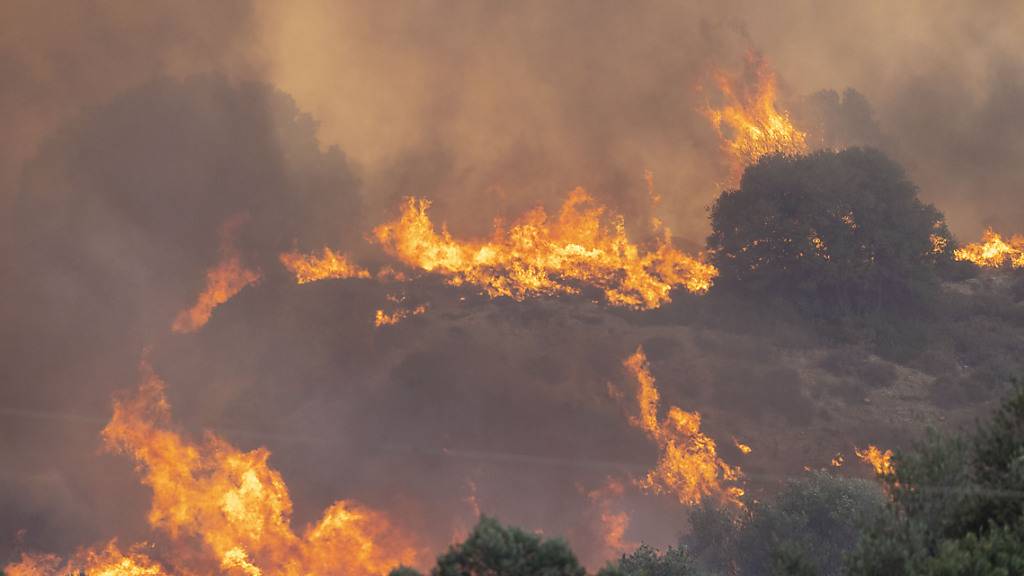 Am Mittag ist Nahe der Ortschaft Gennadi ein neuer Waldbrand ausgebrochen, am Abend erreichen die Flammen eine erste Siedlung, mehrere Häuser werden zerstört. Foto: Christoph Reichwein/dpa
