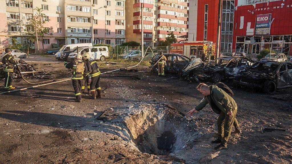 ARCHIV - Einsatzkräfte der Feuerwehr betrachten den Krater nach einem russischen Luftangriff auf ein Wohnviertel in Sumy. Foto: Evgeniy Maloletka/AP/dpa