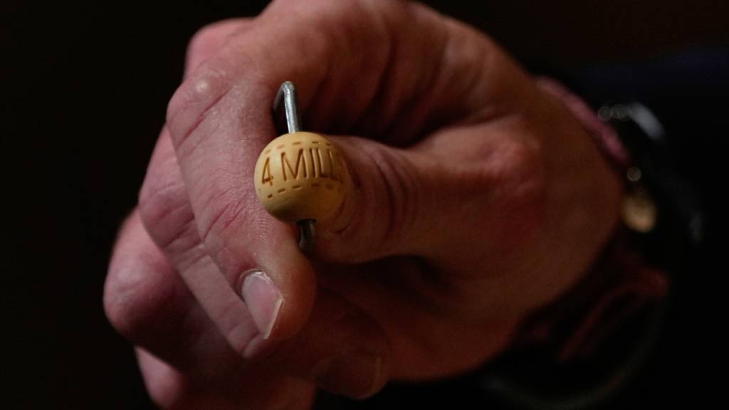 Ein Lottomitarbeiter zeigt eine Lottokugel vor der jährlichen Weihnachtslotterie-Ziehung, bekannt als El Gordo («Der Dicke»), im Madrider Teatro Real. Foto: Manu Fernandez/AP/dpa