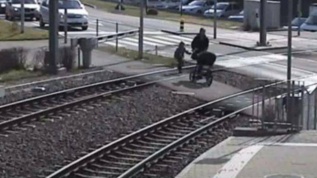 Die Barriere ist unten, eine erwachsene Person mit Kinderwagen und ein Kind überschreiten die Bahngleise: Gegen solche Gefahren startet Aargau Verkehr eine Sicherheitskampagne.