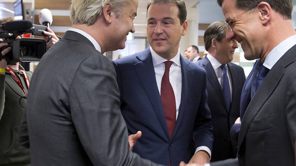 ARCHIV - Geert Wilders (l), Vorsitzender der niederländischen rechtspopulistischen Partei für die Freiheit (PVV) begrüsst Ministerpräsident Mark Rutte (VVD, r) und Vizepremier Lodewijk Asscher (PVDA) bei einem Besuch bei der niederländischen Tageszeitung De Telegraaf. Foto: Peter Dejong/AP/dpa