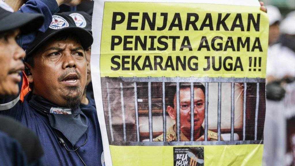 Ein muslimischer Indonesier protestiert mit einem Plakat, auf dem «Verhaftet den Gotteslästerer!» steht. Der christliche Gouverneur der Hauptstadt Jakarta muss sich am Dienstag wegen Blasphemie vor Gericht verantworten.