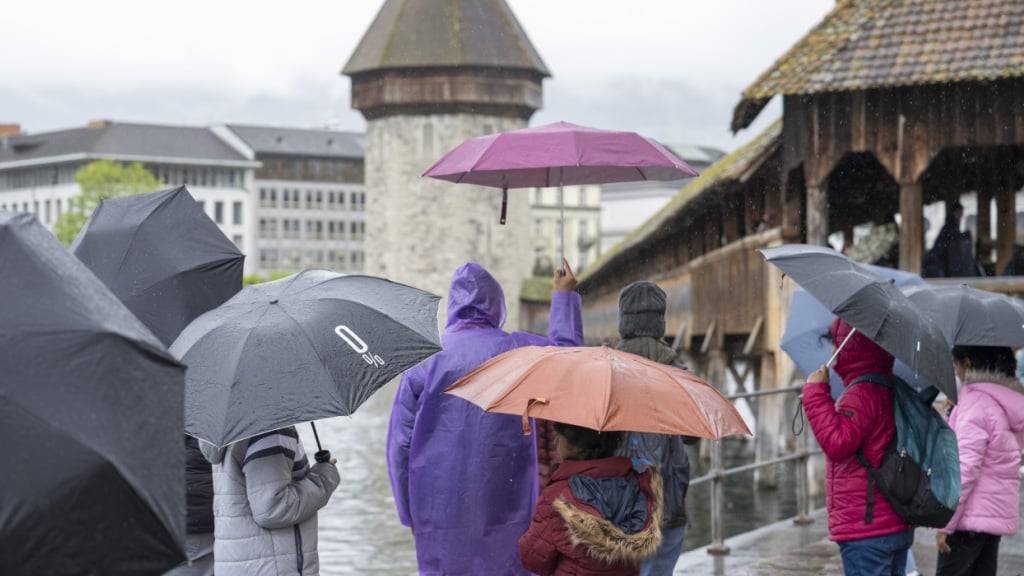 Touristen aus dem asiatischem Raum bei Regen vor der Kapellbrücke in Luzern. (Archivbild)