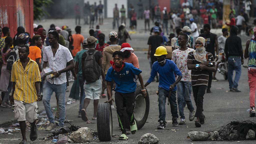 ARCHIV - Während einer Demonstration gegen die Erhöhung der Treibstoffpreise und für den Rücktritt des haitianischen Premierministers Ariel Henry in Port-au-Prince, Haiti, gehen die Menschen mit geplünderten Waren davon. Foto: Odelyn Joseph/AP/dpa