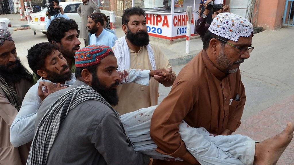 Helfer bringen ein verletztes Opfer des Anschlages in Pakistan in Sicherheit.