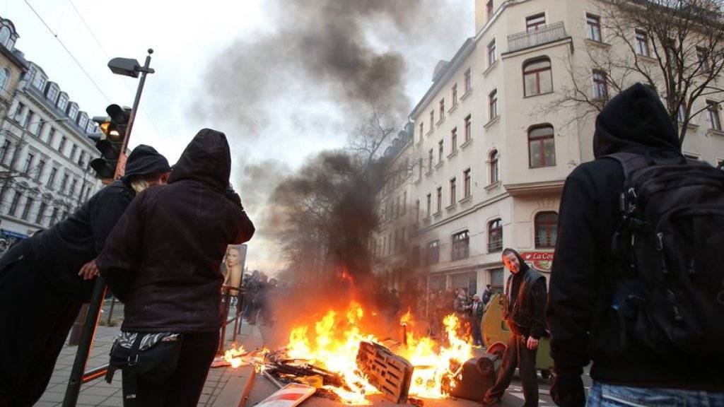 Linke Demonstranten vor einer brennenden Barrikade am Samstag in Leipzig.