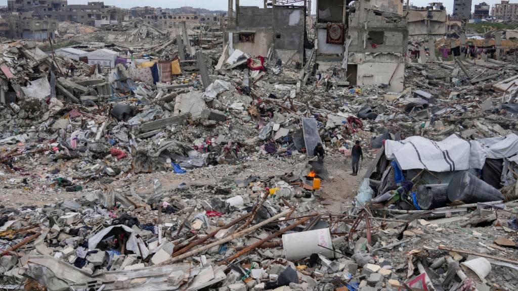 ARCHIV - Menschen gehen im April inmitten der Trümmer von Häusern, die durch die Luft- und Bodenoffensive der israelischen Armee gegen die Hamas zerstört wurden, im nördlichen Gazastreifen. Foto: Abdel Kareem Hana/AP/dpa