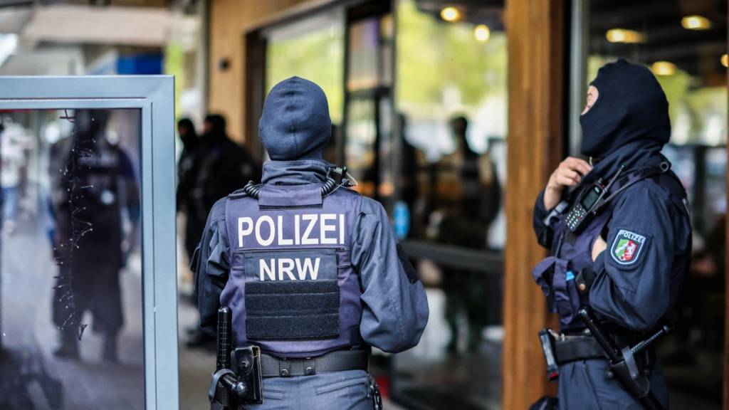 Polizeibeamte stehen vor einem Restaurant am Hamborner Altmarkt, dem vermeintlichen Stammlokal der Mitglieder einer Rockergruppe. Mit einer groß angelegten Razzia geht die Polizei in Deutschland und europaweit seit dem Morgen gegen ein Geldwäsche-Netzwerk und Rocker der «Hells Angels» vor. Foto: Christoph Reichwein/dpa