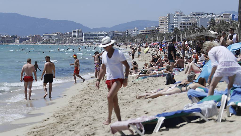 Touristen halten sich am Strand von Arenal in Palma de Mallorca auf. Foto: Clara Margais/dpa