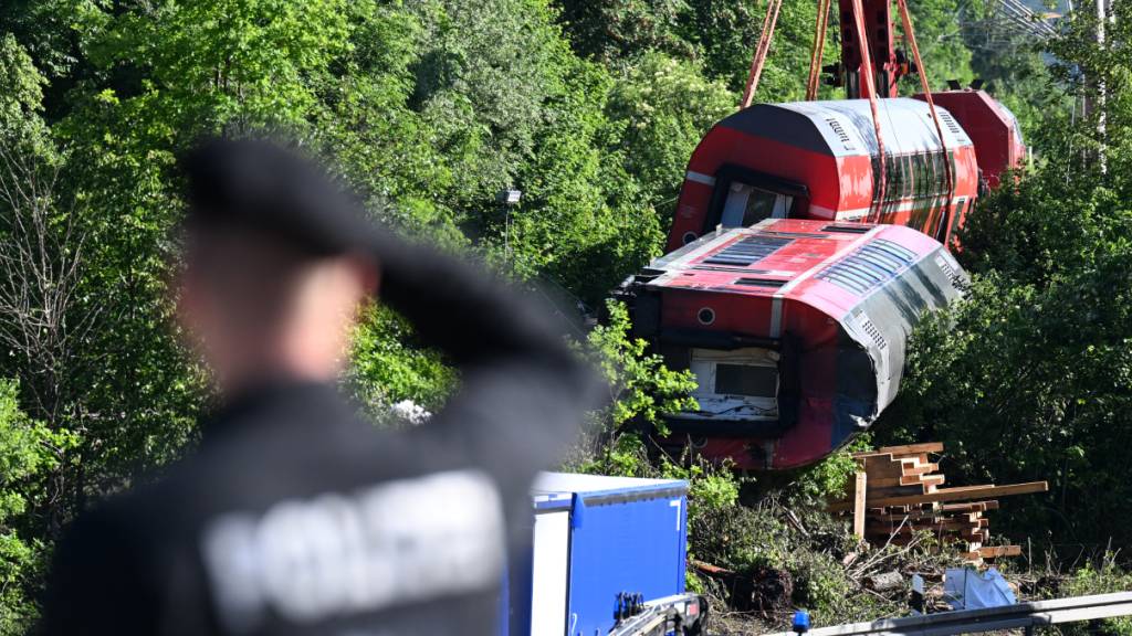 ARCHIV - Ein Polizist betrachtet aus der Ferne den Unfallort, wo zwei Waggons noch geborgen werden müssen. Foto: Angelika Warmuth/dpa
