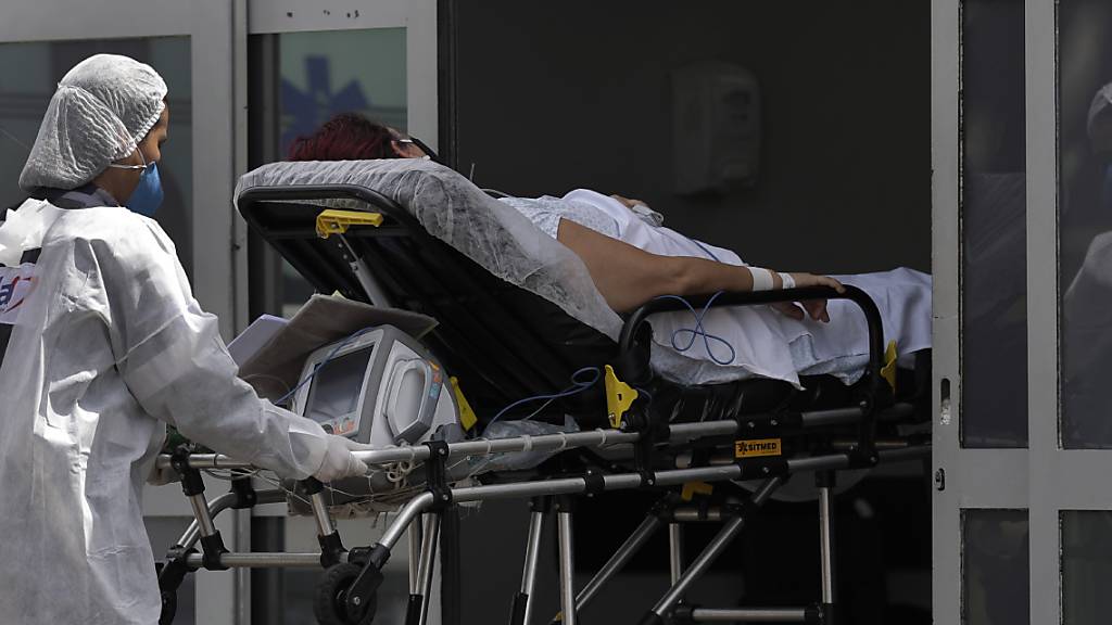 Ein Mitarbeiter des Gesundheitswesens schiebt einen Patienten mit Verdacht auf Covid-19 aus einem Krankenwagen in das öffentliche Krankenhaus HRAN in Brasilia. Foto: Eraldo Peres/AP/dpa