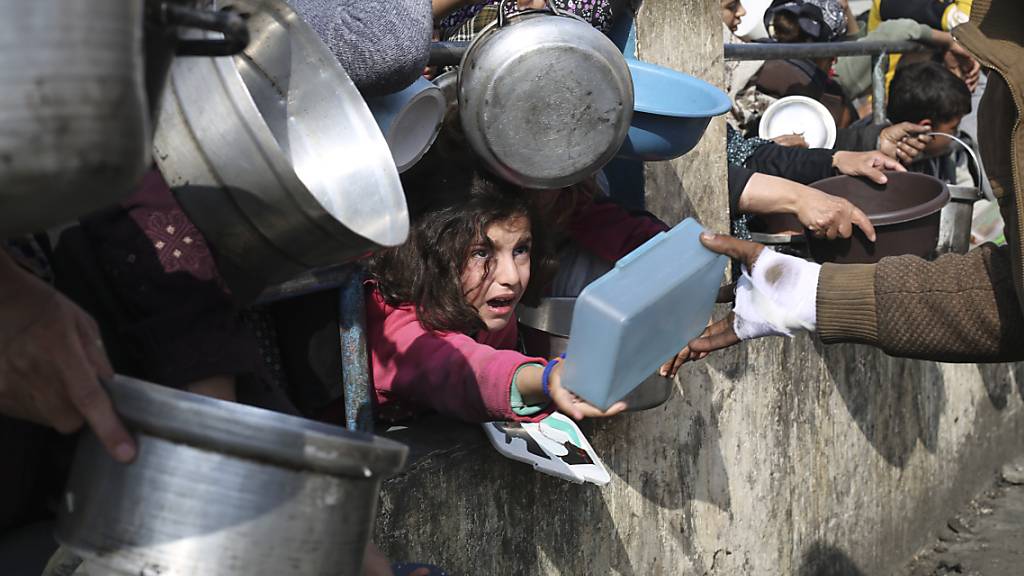 dpatopbilder - Palästinenser stehen während der laufenden israelischen Luft- und Bodenoffensive im Gazastreifen für kostenlose Lebensmittel an. Foto: Hatem Ali/AP/dpa