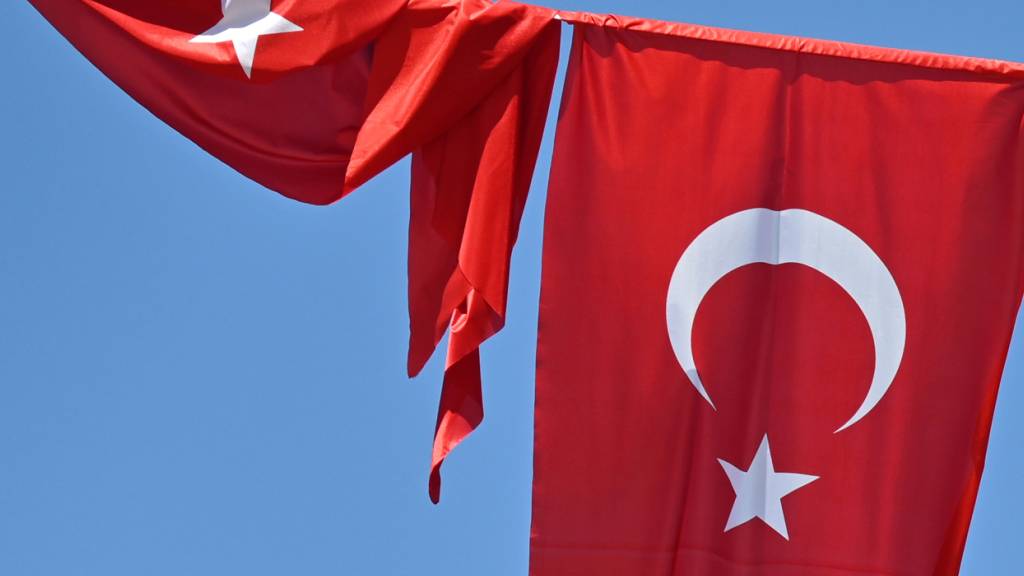 ARCHIV - Eine türkische Flagge weht vor blauem Himmel im Wind, während eine zweite Flagge aufgewickelt daneben hängt. Foto: Anna Ross/dpa