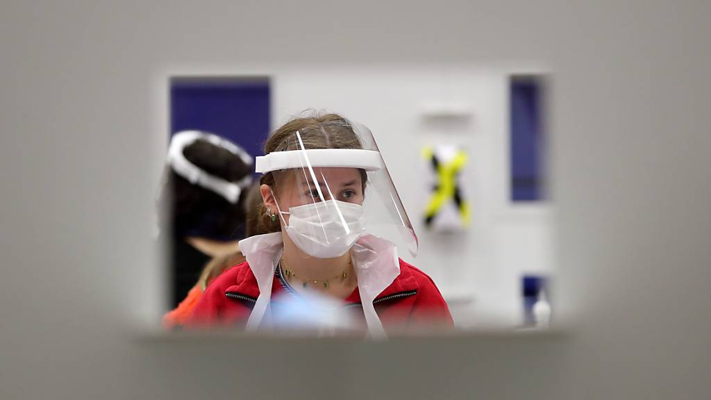 Eine Frau mit Mund-Nasen-Bedeckung und Gesichtsmaske wartet in einem Testzentrum der Universität Edinburgh. Foto: Andrew Milligan/PA Wire/dpa