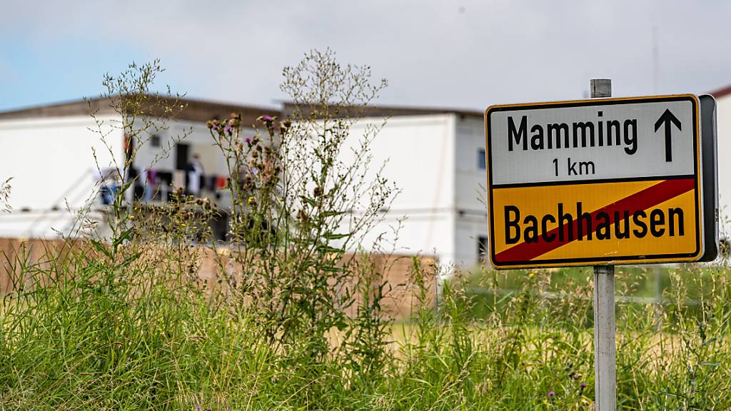 Das Ortsschild von Mamming, im Hintergrund sind die Unterkünfte von Erntehelfern zu sehen. Foto: Armin Weigel/dpa